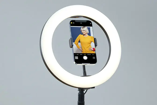 The mobile phone is attached to the ring light.
