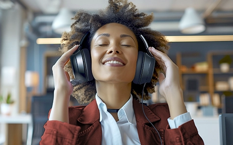 A young woman wears over-ear headphones and listens to the music in a good mood