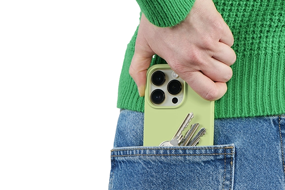 You can see the back of a woman. She is wearing blue jeans and a green knitted jumper. She puts her smartphone and keys in her back pocket.