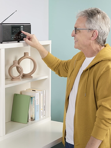 An elderly gentleman cheerfully operates the Hama digital radio "DR2002BT"